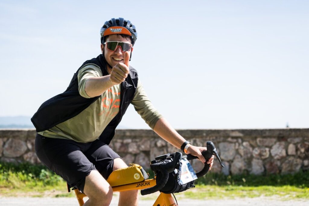 Ciclista sorridente su bici gravel che mostra il pollice in su durante l’evento Unpaved Roads a Punta Ala