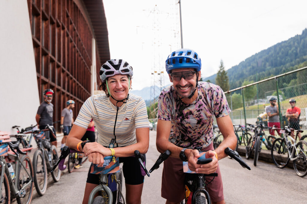 Ritratto di una coppia di ciclisti sorridenti in pausa con le loro bici gravel, pronti per l'avventura.