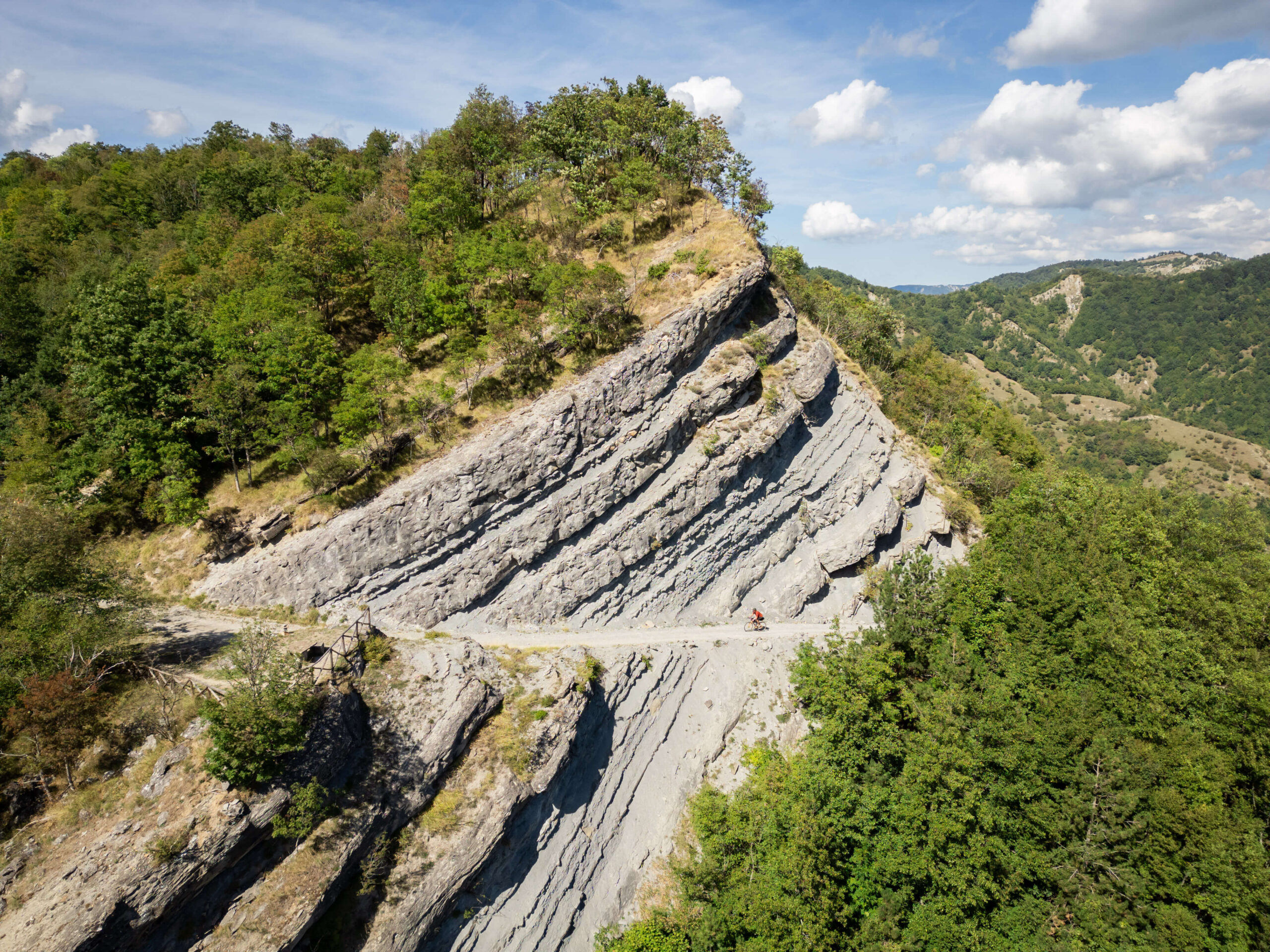 Scatto drone di ciclisti in mountain bike e gravel mentre esplorano i sentieri forestali dell'Appennino Tosco-Romagnolo vicino a Santa Sofia, tappa del circuito Unpaved Roads.